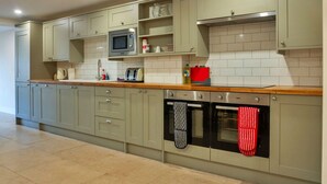 A modern kitchen with light green cabinets, a microwave, a toaster, and an oven. - Wonderful  villa for 6 guests with hot tub, WIFI and pets allowed (Cirencester)