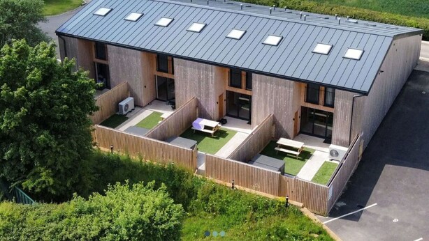 A modern building with a flat roof, multiple windows, and a courtyard with seating. - Wonderful  villa for 6 guests with hot tub, WIFI and pets allowed (Cirencester)