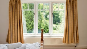 Habitació amb llit, finestra amb cortines i radiador.