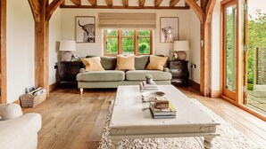 A cozy living room with a sofa, a coffee table, and a view of greenery outside.