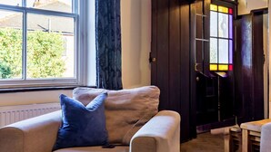 Ein gemütliches Wohnzimmer mit Sofa, Fenster und einer Haustür mit Buntglasverzierungen.