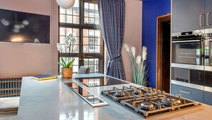 A modern kitchen with a central island, stainless steel appliances, and a large window with curtains. - Stunning  villa for 12 guests with WIFI, hot tub and terrace (Nottingham)