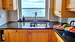 Une cuisine avec des meubles en bois, un évier en acier inoxydable et une vue sur l’eau.