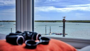 Une vue sur la mer, prise depuis une fenêtre, avec une paire de jumelles posée sur un coussin.