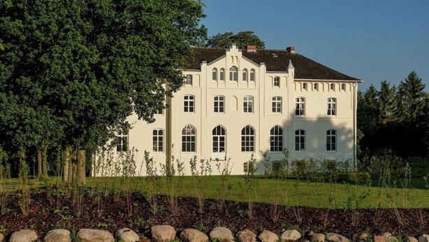 Een groot, wit, twee verdiepingen hoog gebouw met veel ramen en een symmetrische gevel.