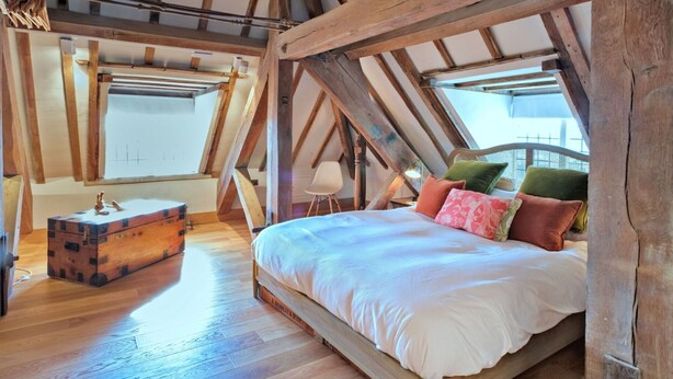 An attic bedroom with a wooden bed, a chest of drawers, and a view of the outside through a window. - Lovely apartment for 3 guests with WIFI (Brackley)