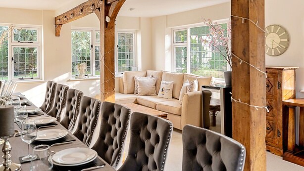 A dining area with a wooden trellis, a sofa, and a clock on the wall. - Beautiful  villa for 16 guests with WIFI, hot tub and pets allowed (Aylesbury)