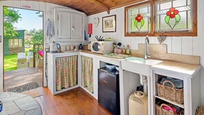 A compact kitchen with wooden ceiling, white cabinets, a built-in dishwasher, and a window with floral stained glass. - Stunning  villa for 4 people with pets allowed (Romsey)