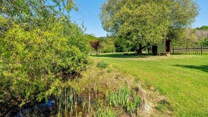 A grassy area with a large tree, a small structure, and a fence. - Stunning  villa for 4 people with pets allowed (Romsey)