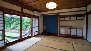 A traditional Japanese room with tatami flooring, sliding doors, and a view of greenery outside. - OMISHIMA SPACE HANARE (Imabari)