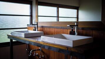 A bathroom with two sinks, wooden cabinets, and a window with a view of the water.