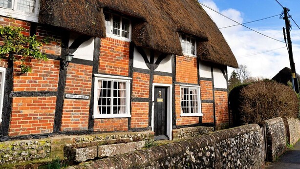 A traditional half-timbered house with a thatched roof, a stone wall, and a sign indicating it is a cottage. - Wonderful  villa for 4 guests with WIFI, terrace and pets allowed (Chilton Foliat)