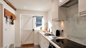 A modern kitchen with a built-in oven, a stovetop, and a window with a view of the outdoors. - Wonderful  villa for 4 guests with WIFI, terrace and pets allowed (Chilton Foliat)