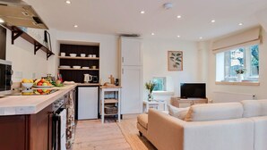 A compact living space with a kitchenette, a sofa, a TV, and a window with a view.