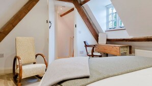A bedroom with a sloped ceiling, a bed, a desk, and a chair.