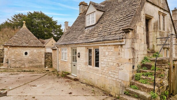 A stone building with a steeply pitched roof, a small window, and a door.