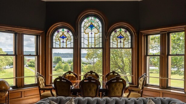A room with a large window, a dining table with chairs, and a tufted sofa. - The Royal Tay Apartment - Stained Glass and River Views (Dundee)