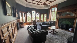 A room with a fireplace, a sofa, a table, and a globe. - The Royal Tay Apartment - Stained Glass and River Views (Dundee)