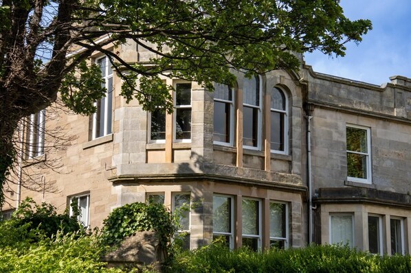 A stone building with multiple windows and a corner entrance.