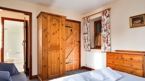 A bedroom with a bed, wooden wardrobe, and a dresser.