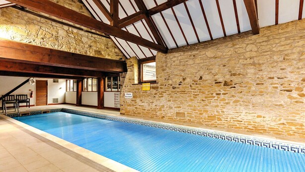 An indoor swimming pool with stone walls and wooden beams.
