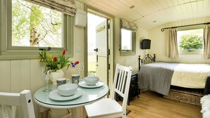Une pièce confortable avec un lit, une table à manger avec des chaises et une fenêtre avec des rideaux.