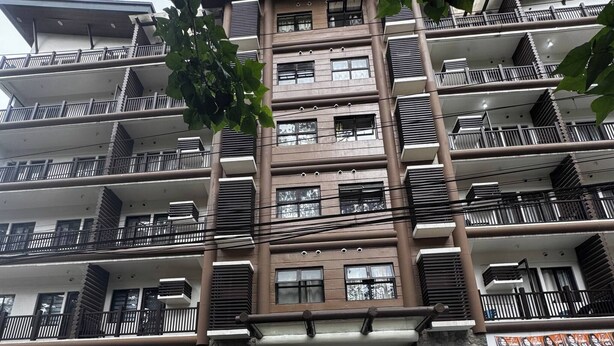 A multi-story residential building with balconies and a stone entrance. - Cozy Brenthill Condo in Baguio City - Entire House Rental (Baguio)