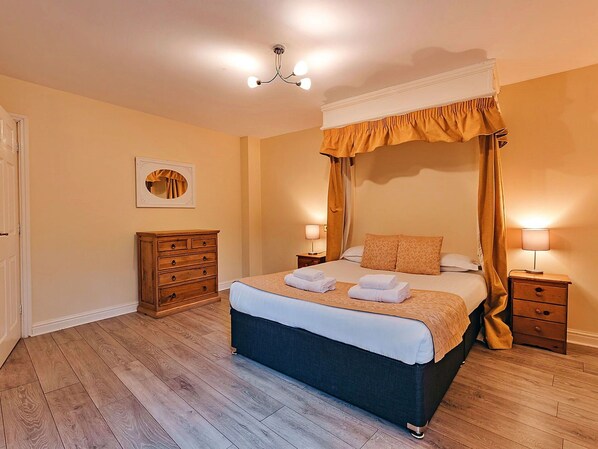 A bedroom with a four-poster bed, a wooden dresser, two bedside tables with lamps, and a ceiling light fixture. - Wonderful  villa for 2 guests with WIFI, TV and pets allowed (Shrewsbury)