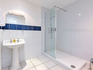 Ein Badezimmer mit einer Duschkabine, einem Standwaschbecken und blauen Fliesen.