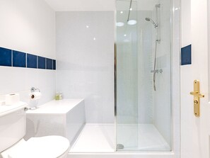 Ein modernes Badezimmer mit einer gläsernen Duschkabine, einem weißen Waschbecken und einer Toilette.
