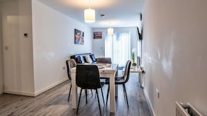 A modern dining area with a wooden table, chairs, and pendant lighting. - Cosy apartment for 3 guests with WIFI (Birmingham)