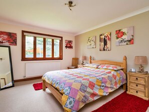 A bedroom with a wooden bed, a window, a radiator, a mirror, and artwork on the walls.