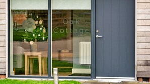A modern building with a large glass door and a dark blue door. Inside, there is a Christmas tree with ornaments and a sign that reads "The Heart of England Forest." - Beautiful  villa for 8 people with WIFI, TV and pets allowed (Alcester)