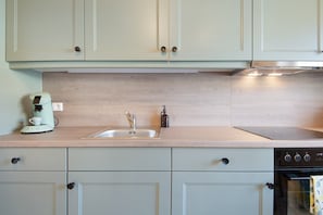 A kitchen with light-colored cabinets, a stainless steel sink, a coffee maker, and a dishwasher.