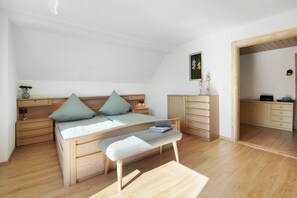 A bedroom with a bed, bedside tables, a bench, a dresser, and a desk.