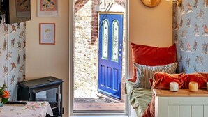 A cozy room with a blue door, a wooden stove, a rug, and a bench with cushions. - Beautiful  villa for 4 people with terrace (Shrawardine)