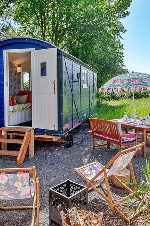 Siirrettävä asunto, jossa on pieni kuisti, ruokapöytä ja ulkotilaa istumiseen.