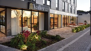 A hotel exterior with a modern design, large windows, and outdoor seating area. - Vallér Parque Hotel Executive (Lajeado)