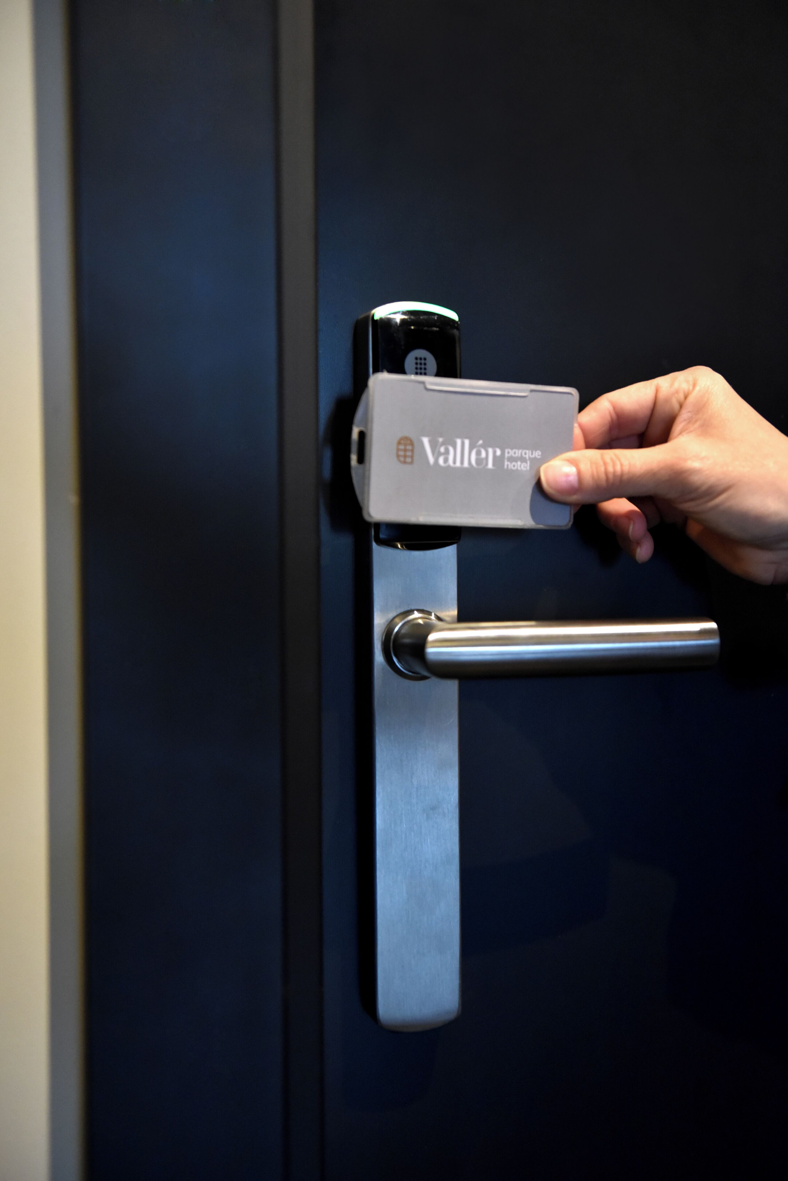 Una mano operando la cerradura de una puerta con una tarjeta llave identificada como 'Valler parque hotel'.