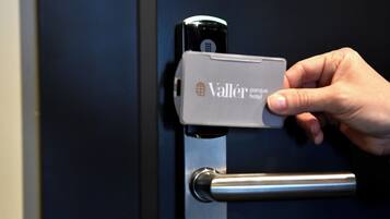 A hand operating a door lock with a key card labeled "Valler parque hotel".