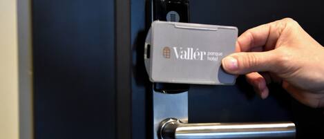 Una mano operando la cerradura de una puerta con una tarjeta llave identificada como 'Valler parque hotel'.