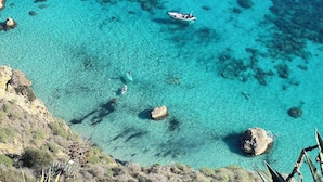 A coastal landscape with clear turquoise waters, rocky outcrops, and a boat.