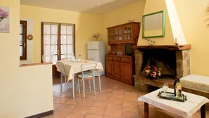 A dining area with a table and chairs, a refrigerator, a wooden cabinet, and a fireplace.