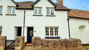 A two-story house with a white exterior, a black door, and a stone wall in front. - Stunning  villa for 6 guests with WIFI (Minehead)