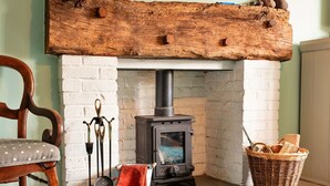A rustic room with a wood-burning stove, a chair, a bucket, and a basket. - Stunning  villa for 6 guests with WIFI (Minehead)