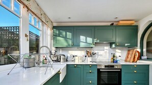 A kitchen with teal cabinets, a white countertop, and a wooden floor.