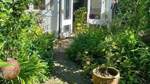 A garden pathway leading to a white house with a brick facade and a conservatory.