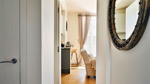 Un pasillo que conduce a un comedor con una mesa y sillas, un espejo en la pared y una puerta a la izquierda.
