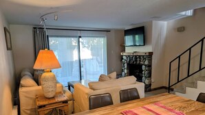 A living room with a sofa, a coffee table, a fireplace, and a TV mounted on the wall.