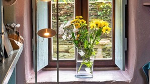 Une pièce avec une fenêtre, un vase de fleurs et un lampadaire.